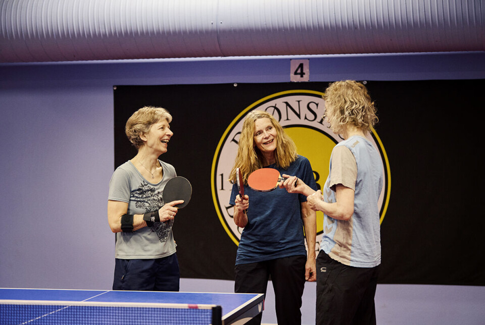 I Grøndal Centret mødes seniorere til bordtennistræning - og hyggeligt samvær. Her ses tre kvindelige spillere, som står ved et af bordene og snakker.