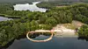 Dronebillede fra Almind Sø i Silkeborg. Her ses to runde badebroer, som er omgivet af skov.