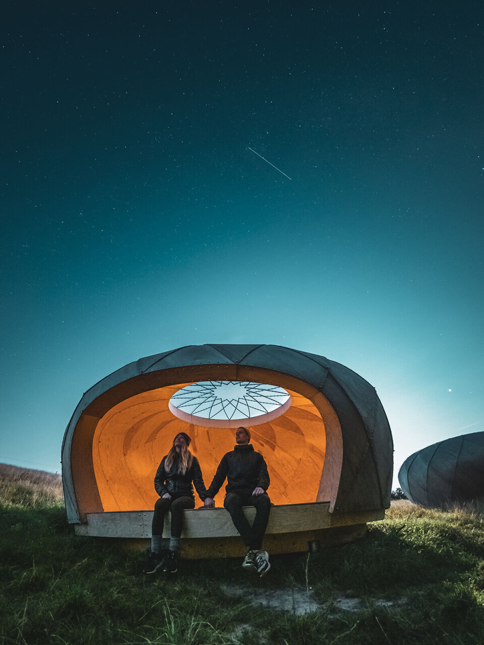 Shelter ved observatoriet i Brorfelde. Her ses to personer, der sidder i et shelter i tusmørke.