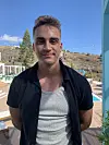 Jonas fra Love Island står og smiler med poolen og bjergene i baggrunden