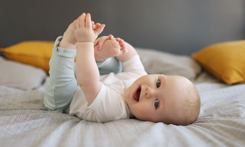 Baby smiler på en seng