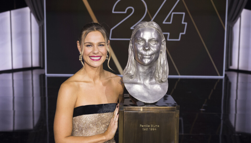 Pernille Blume i flot kjole på scenen foran sin byste