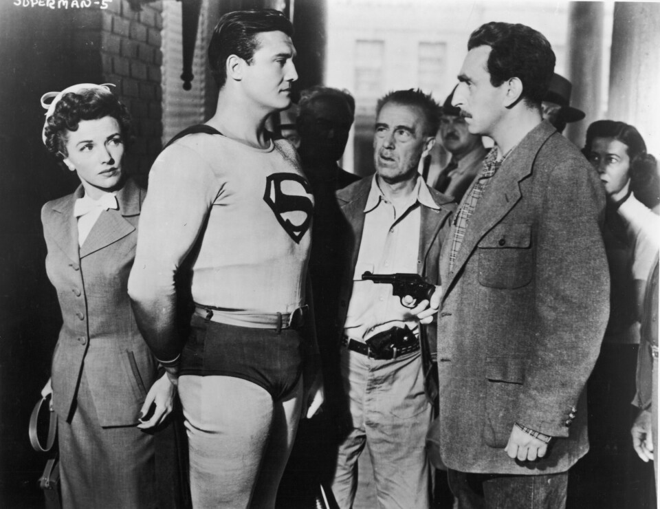 American actor George Reeves (1914 - 1959), as Superman, stands in front of actor Phyllis Coates, as Lois Lane, while a man points a gun at him in a still from the television series, 'Adventures of Superman,' c. 1952. (Photo by Hulton Archive/Courtesy of Getty Images)