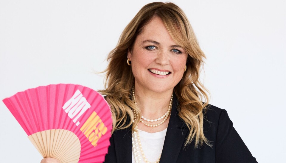 Annamette Fuhrmann står med en vifte i hånden og smiler.