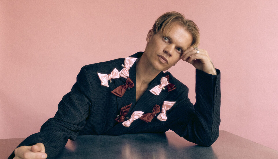 Designer Soeren Le Schmidt sidder ved bord med brystkræftsløjfer.