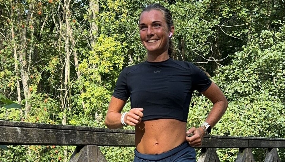 Løbecoach Sissel Møller løber på en bro i naturen.