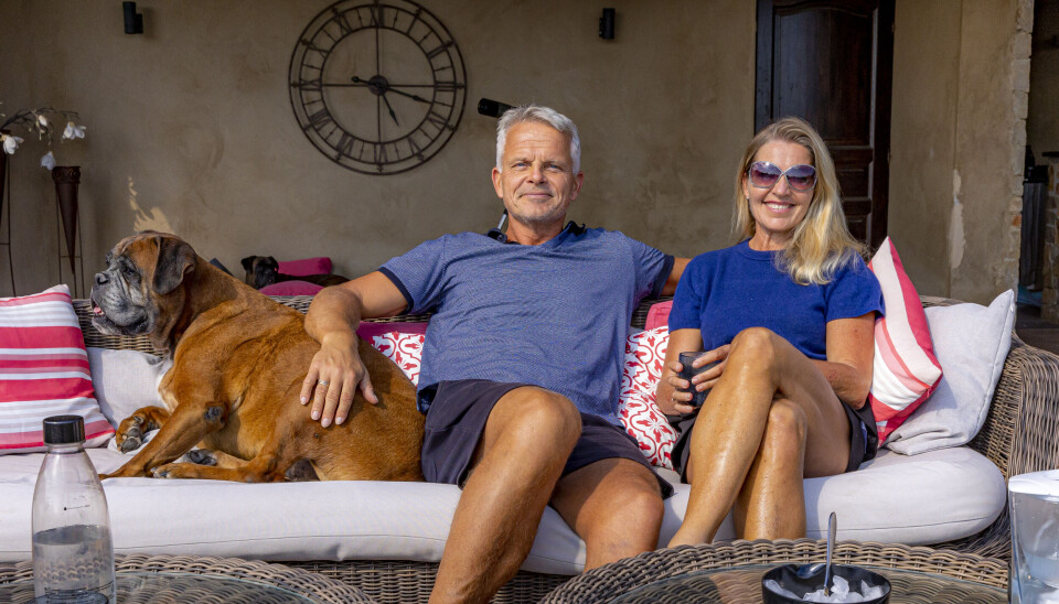 Jakob og Christine sidder i et sofahavemøbel side om side sammen med deres boxer-hund.