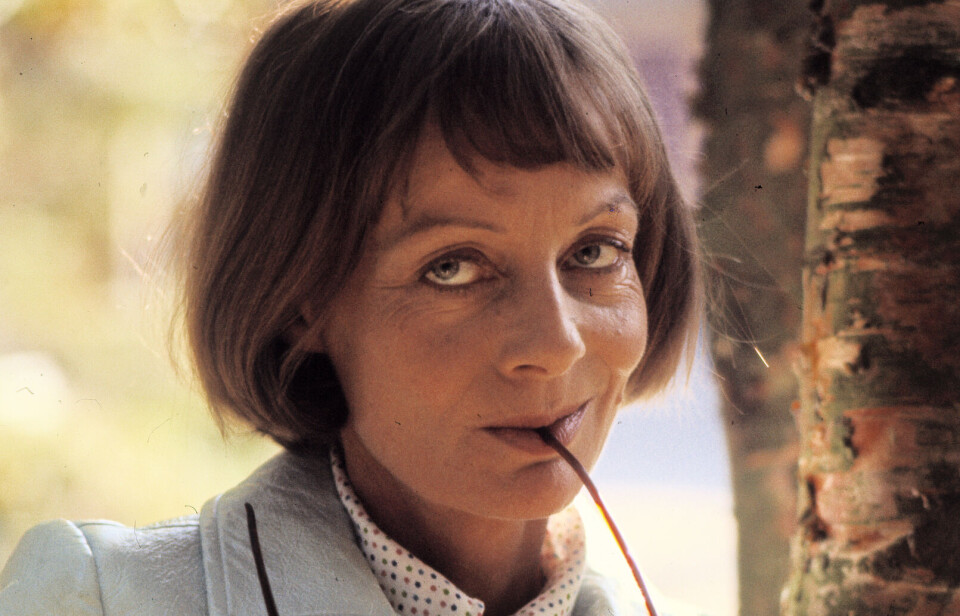 Birgitte Federspiel med sine solbriller i munden og kigger ind i kameraet.