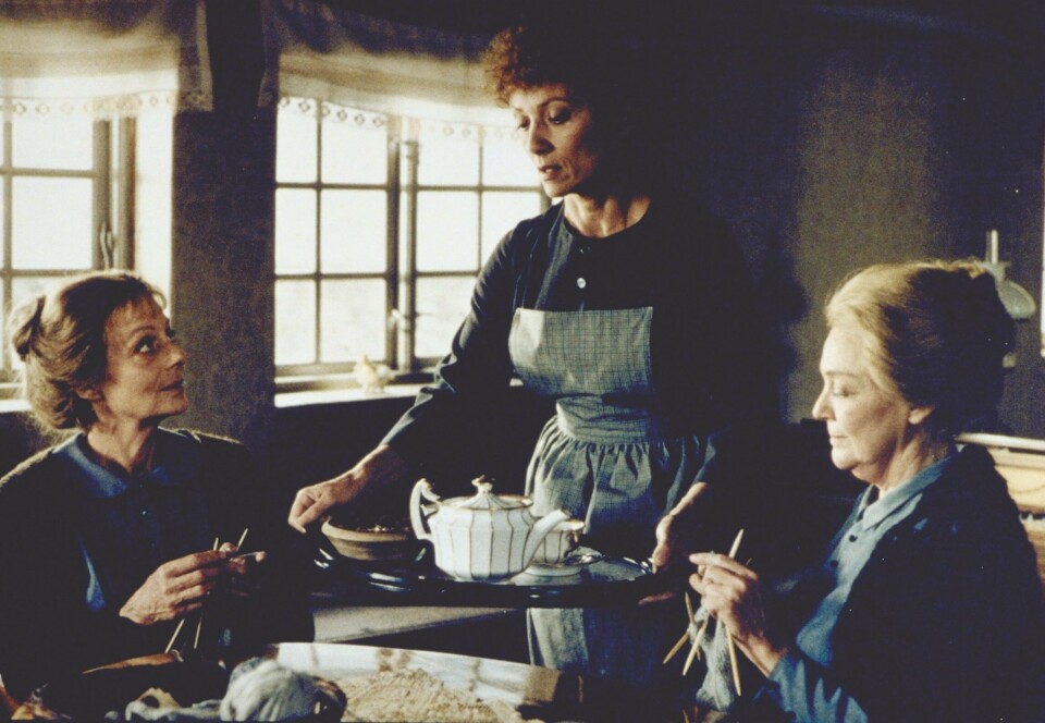 Scene fra filmen 'Babettes gæstebud', hvor søstrene sidder ved et bord og skænker te.