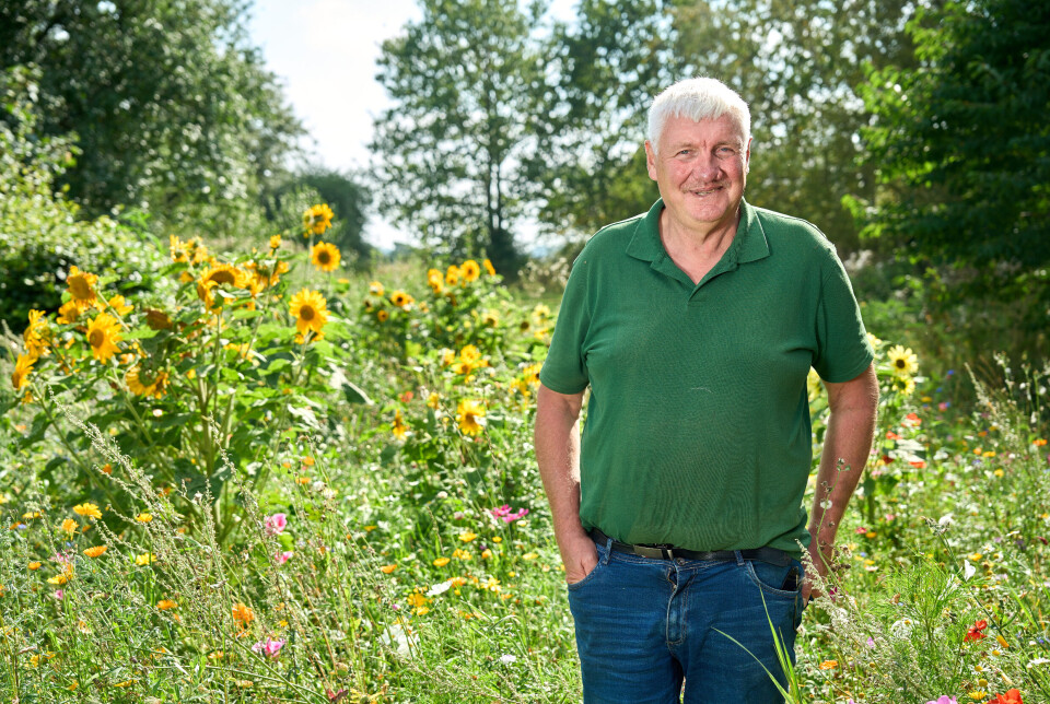 Lars står foran vilde blomster og smiler ind i kameraet.