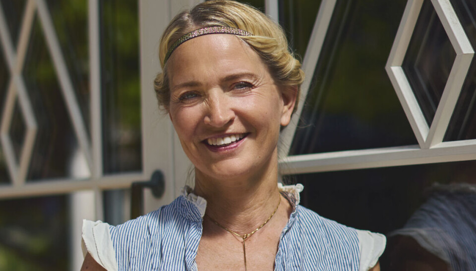 Annette Heick er iført jeans og en blå top og smiler i solen