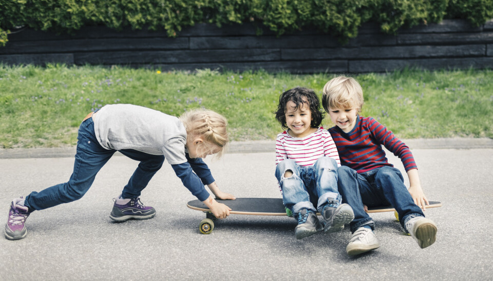 Tre børn leger på skateboard.