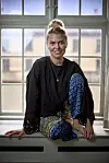 Anna Stokholm sidder i vindueskarmen og smiler ind i kameraet.
