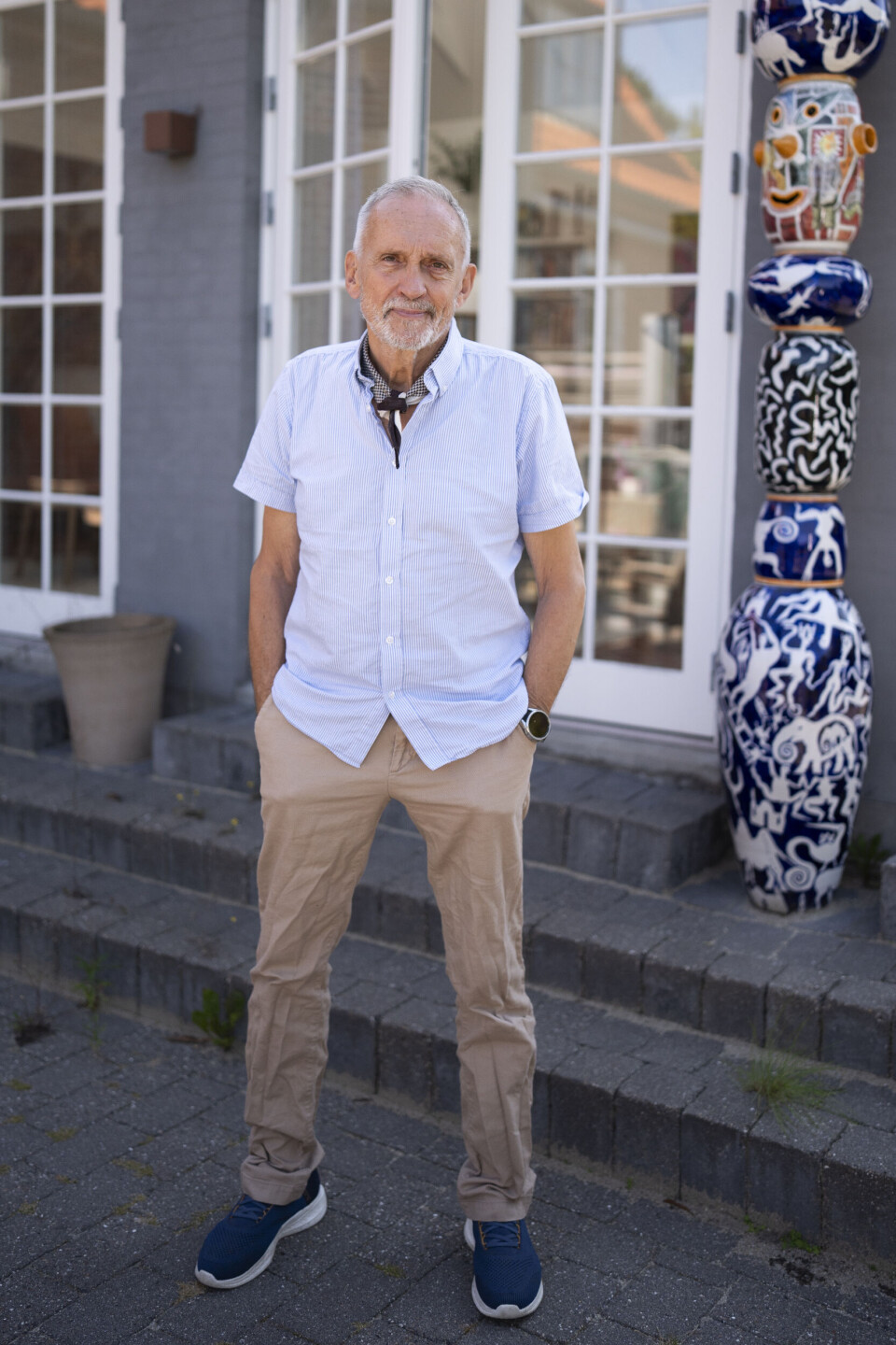 Jussi Adler iklædt brune bukser og en kortærmet, blå skjorte.