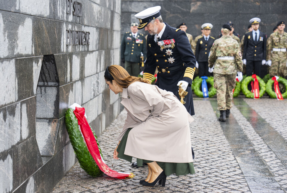 Billede 6 - Dronningen sidder på hug i en beigefarvet trenchcoat, mens hun retter på kransens bånd.