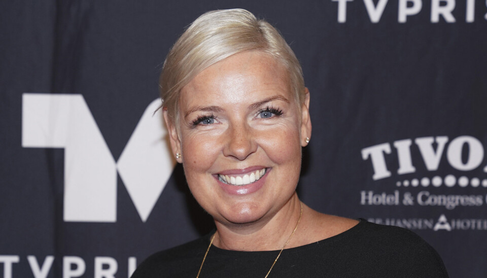 Tina Bilsbo smiler ind i kameraet iklædt sort kjole og lang guldhalskæde.