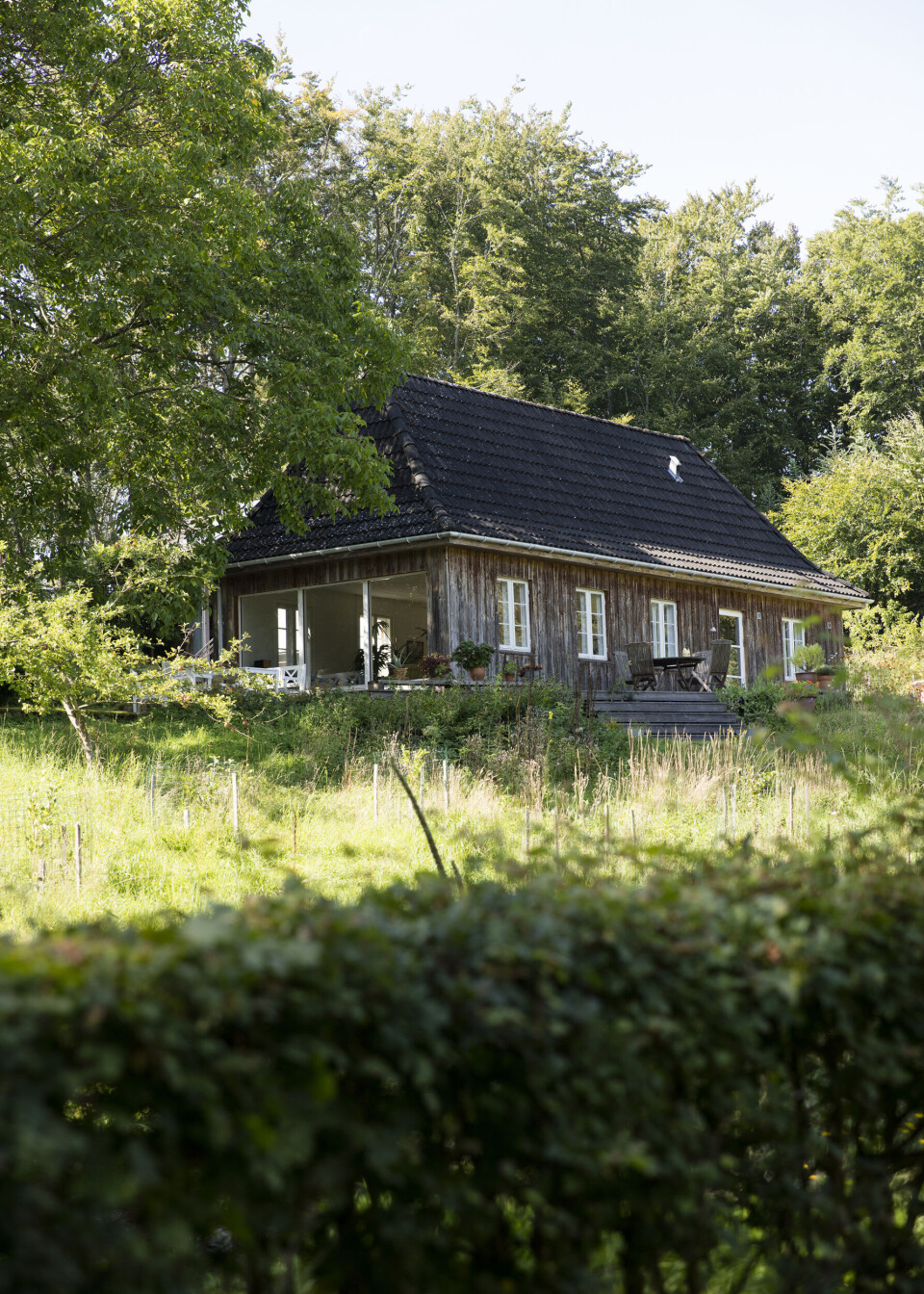 Vue fra køkkenhave til hovedhus. Huset er oprindeligt en jægerhytte, som er gået i arv i generationer. Efter flere istandsættelser er den nu et pragtfuldt familiehus, blandt andet blev de tre store panoramavinduer tilføjet midt i 1990'erne, så naturen blev lukket ind i stuen.