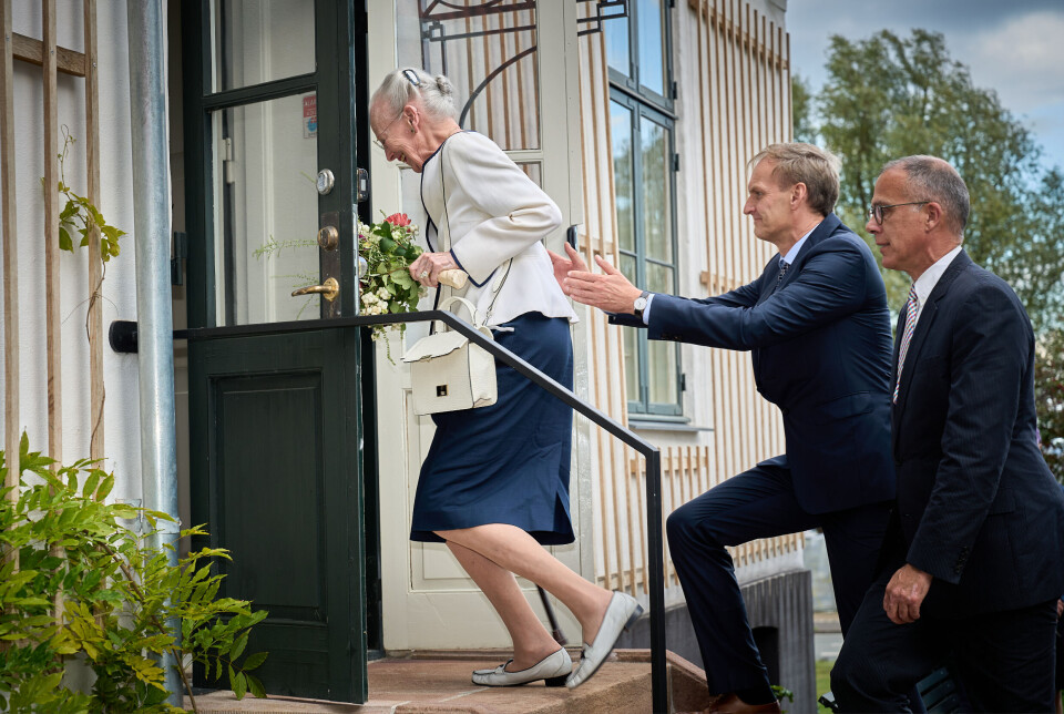Dronning Margrethe på vej op ad trappen iklædt blå nederdel og hvid jakke.