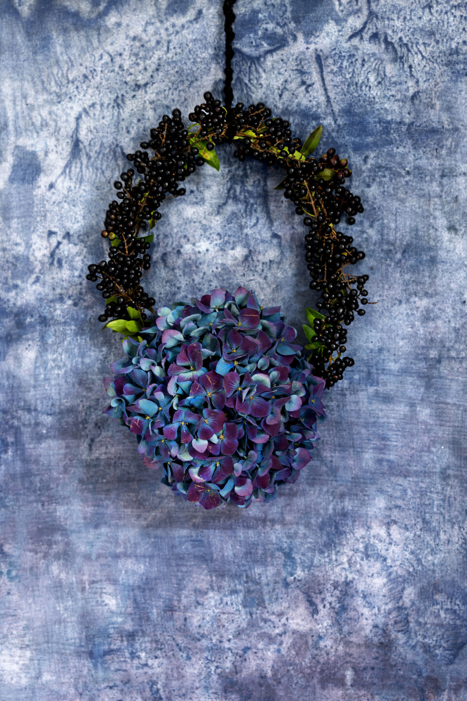 Fra hæk til høstkrans: Lav en utraditionel krans af glinsende frugter fra liguster og en prægtig blomsterstand fra hortensia. Dan en oval form, ca. 15 x 18 cm, i kraftig ståltråd, og sno blomstertape om den. Fastgør hortensia med blomstertråd, og bind ligusterkviste om den resterende del. Sæt bånd i til ophæng.