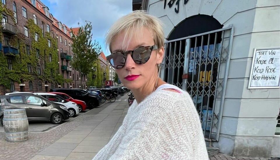 Betina Holte cykler på en sort cykel. hun har kort, lyst hår, solbriller på og en kraftig lyserød læbestift.