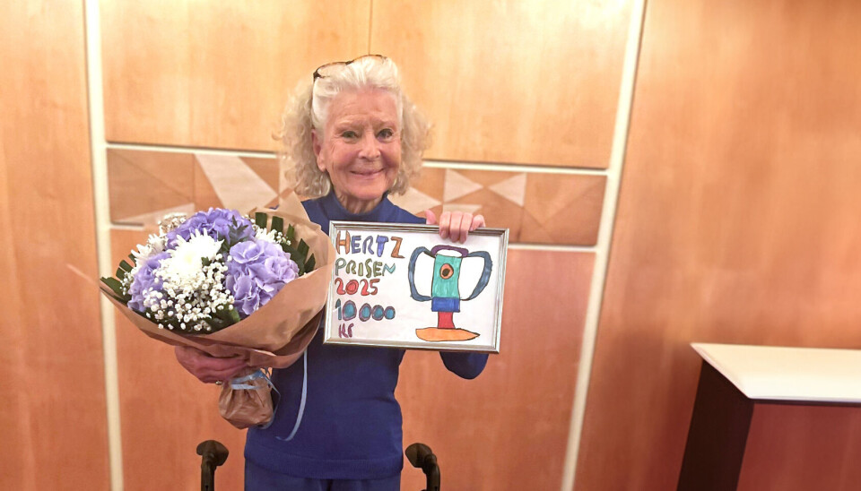 Lone Hertz står bagved sin rollator og viser stolt prisen frem og har en buket blomster i hånden.