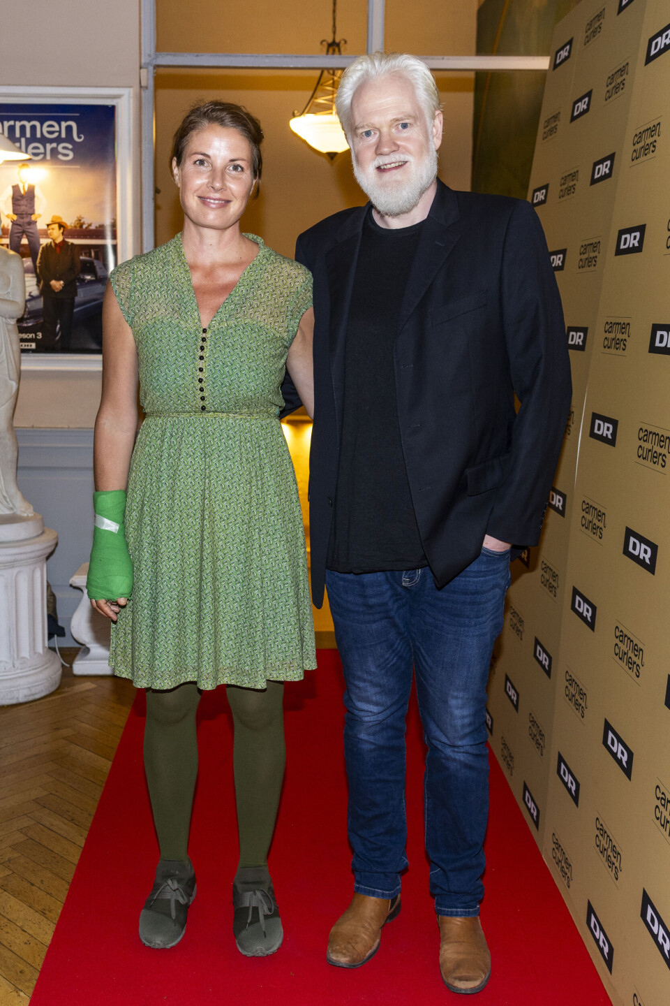 Esben Dalgaard holder om sin hustru, der er ikædt en grøn kjole og matchende gips.