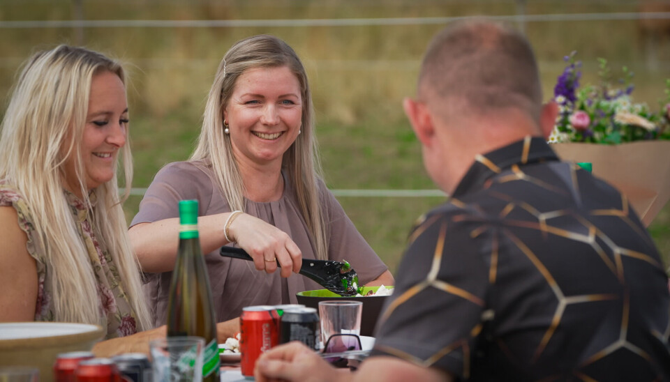 De sidder ved et havebord og spiser grillmad.