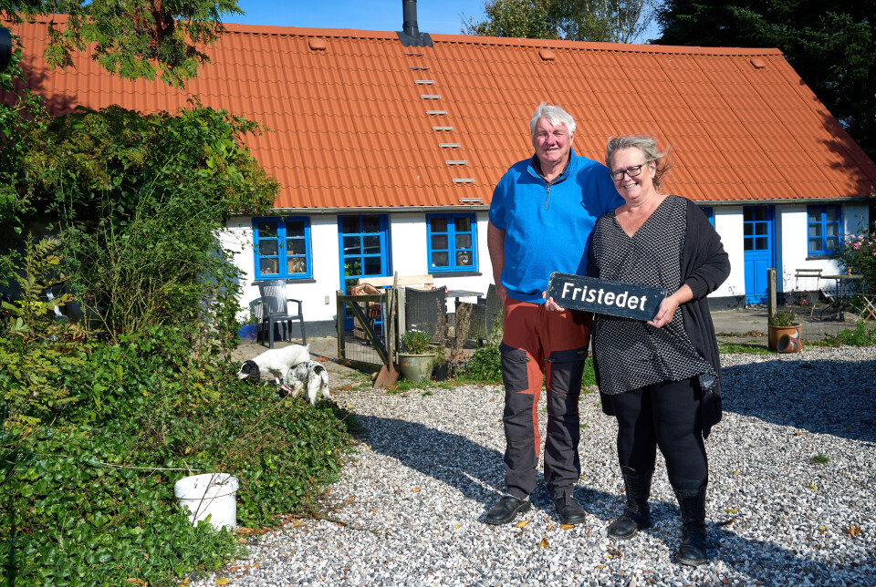 Gitte viser ét af skiltene frem, mens hun står ved siden af Lars foran huset i Randers.