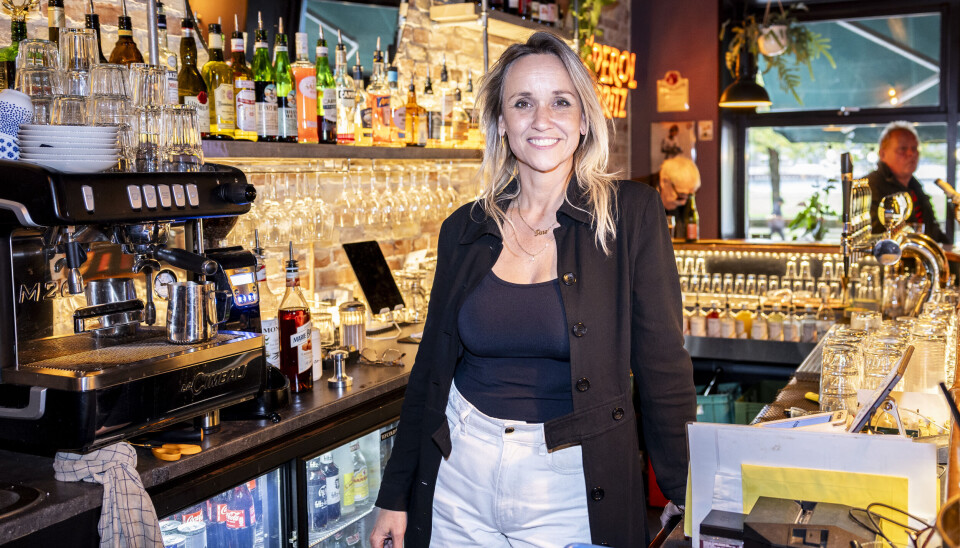 Tine Hartlev står bag baren og smiler.