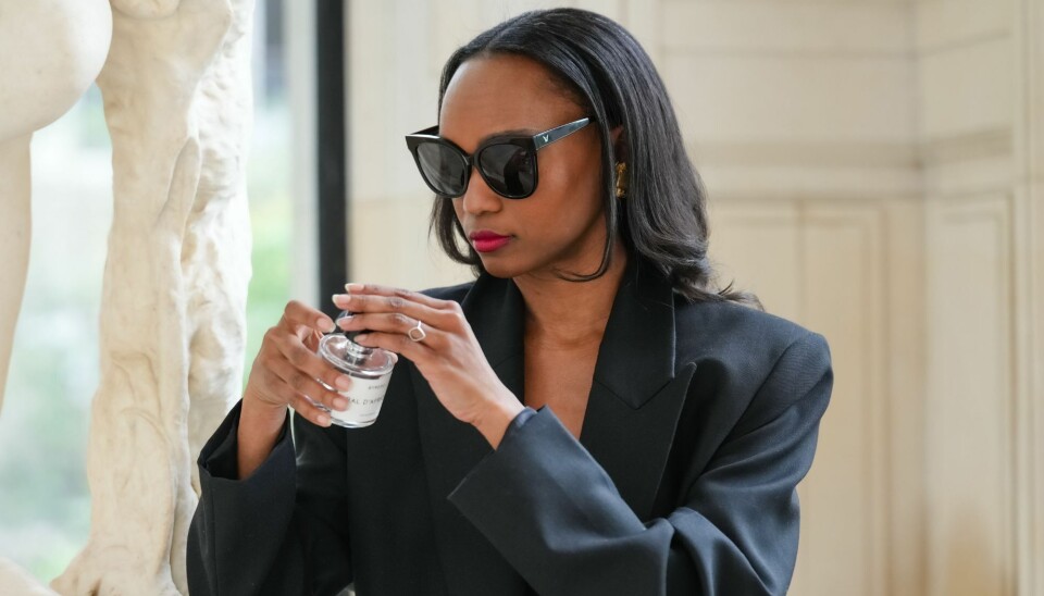 En kvinde står med en parfumeflaske i sin hånd.