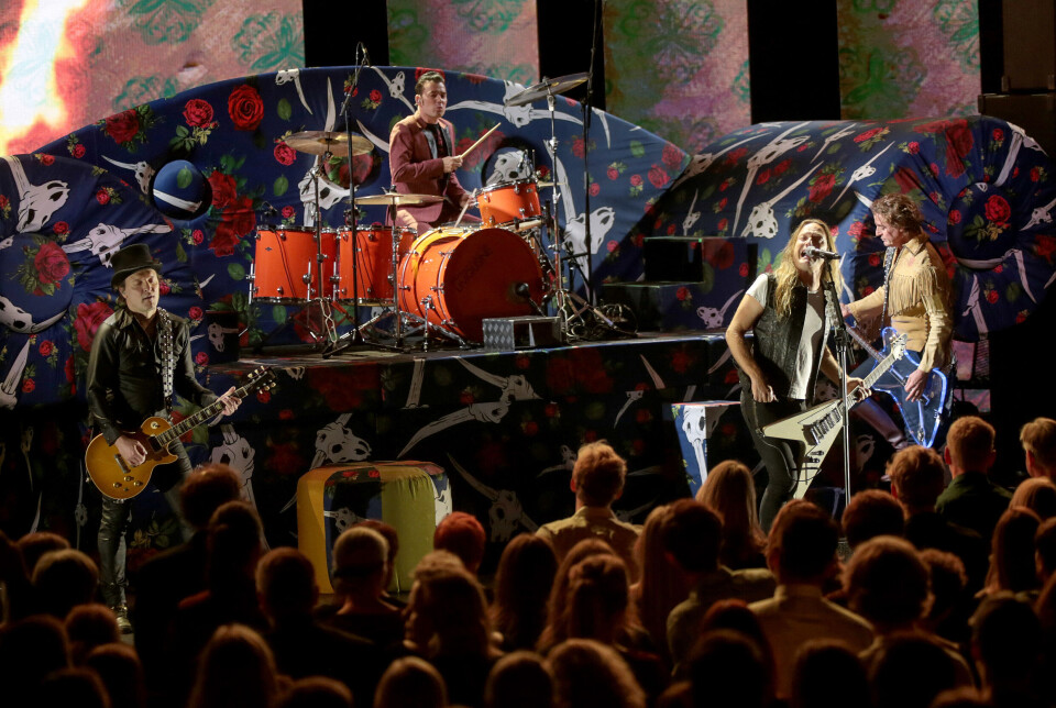 Foto fra D-A-Ds koncert med publikum i forgrunden og bandet på scenen.