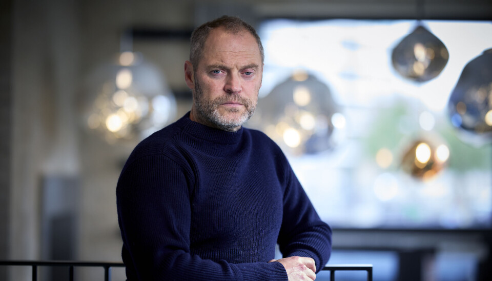 Jacob læner sig op ad et gelænder i en mørkeblå trøje.