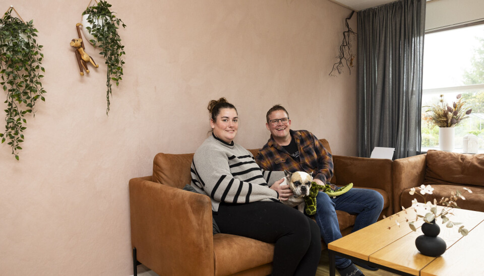 Parret sidder i sofaen og smiler.