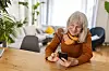 Ældre kvinde kigger på sin telefon.