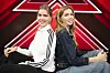 Sara og Marie Esmark sidder ryg mod ryg foran et stort rødt X Factor-logo.