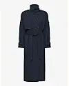Lang mørkeblå trenchcoat med høj krave og bindebælte mod lys baggrund.