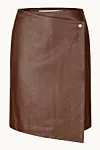 Brun lædernederdel med asymmetrisk front og metalknap mod lys baggrund