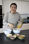 Micki Cheng blander cornflakes og slik i skåle på køkkenbordet under et interview.