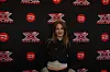 Person står foran sort pressevæg med X Factor- og TV 2-logoer.