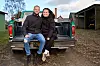 Christian og Terese sidder på ladet af en grøn pickup på en gårdsplads