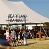 Folk går mod et stort festivaltelt med skiltet Heartland Banquet på en solrig dag.