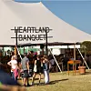 Folk går mod et stort festivaltelt med skiltet Heartland Banquet på en solrig dag.