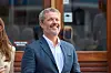 Kong Frederik står udendørs i Gråsten og smiler under et officielt arrangement.