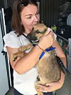 Kvinde krammer en hund med blåt halsbånd i et depotlignende rum