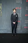 Mikkel Boe Følsgaard står i jakkesæt foran en grå Netflix-fotovæg ved premiereevent