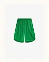 Grønne, løstsiddende bermudashorts på lys baggrund.