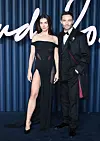 Amy Jackson Westwick og Ed Westwick står i elegante sorte outfits på den blå løber ved The Fashion Awards 2025.