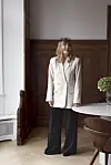 Anette Kristine Poulsen i blazer står smilende i et rum med træpaneler og rundt bord.