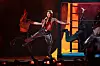 Søren Torpegaard Lund danser energisk på en rødoplyst Eurovision-scene med backupdansere.