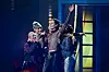 Søren Torpegaard Lund synger på Eurovision-scenen omgivet af medperformere i farverigt lys.